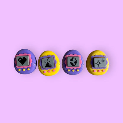 Four colorful vintage-style toys with screen displays on a pink background