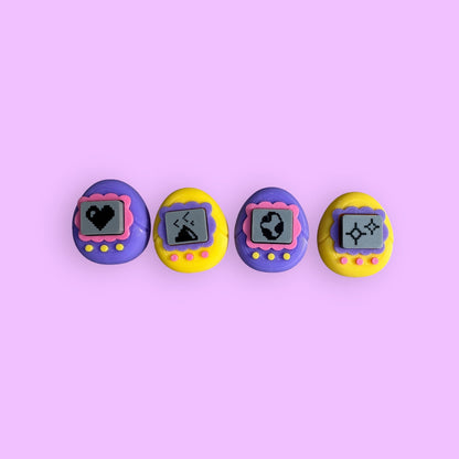 Four colorful toy devices with digital displays on a pink background