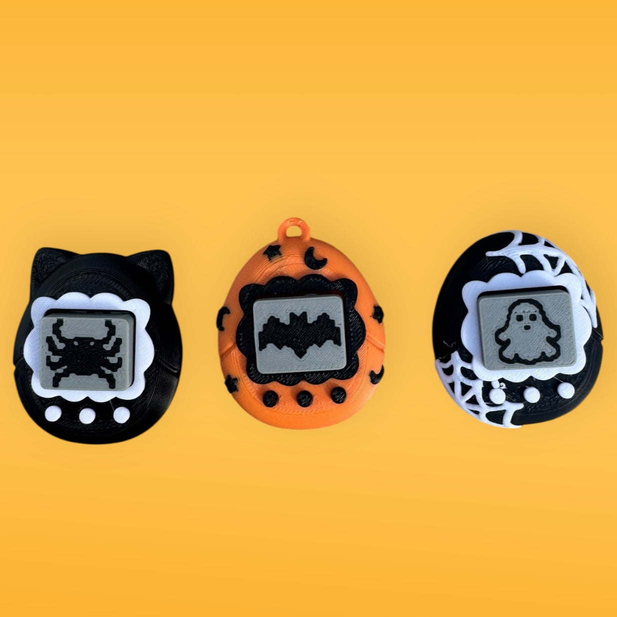 Three Halloween-themed Tamagotchi-style figurines on a yellow background