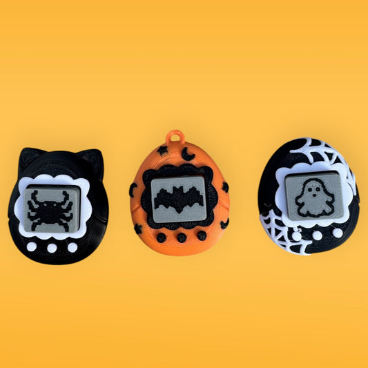 Three Halloween-themed Tamagotchi-style figurines on a yellow background